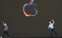 Tim Cook leaves a stage with a large Apple logo as Craig Federighi arrives from the other side