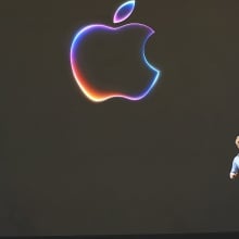 Tim Cook leaves a stage with a large Apple logo as Craig Federighi arrives from the other side