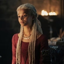 Rhaena Targaryen sitting in a hall in Dragonstone, wearing a red dress.