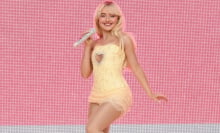 Sabrina Carpenter beaming on stage in a yellow dress. 