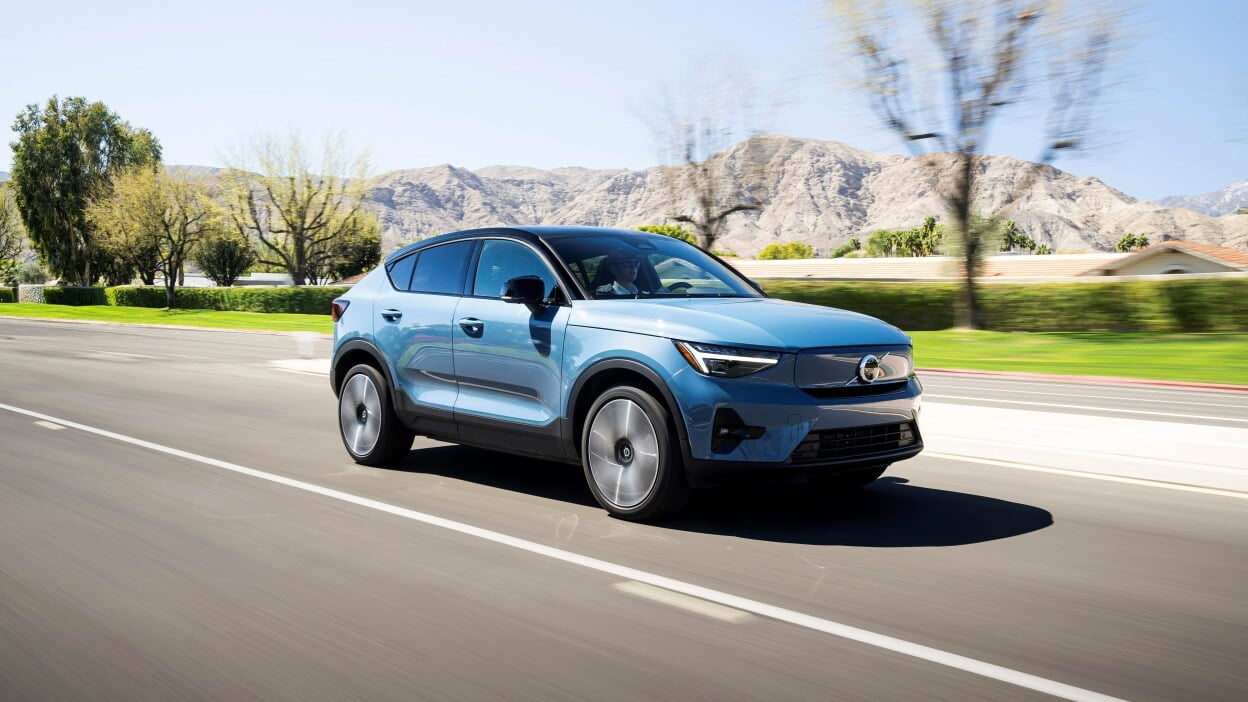 A blue car on the road with a desert background.