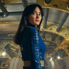 Ella Purnell (Lucy) stands in a vault corridor wearing a blue and yellow jumpsuit in "Fallout".