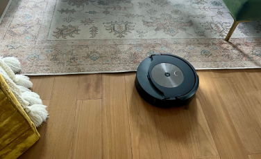 iRobot Roomba Combo j9+ mopping hardwood floor by rug with yellow chair and green couch in peripherals