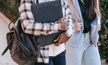 Bodies of two people, one carrying a laptop and a backpack