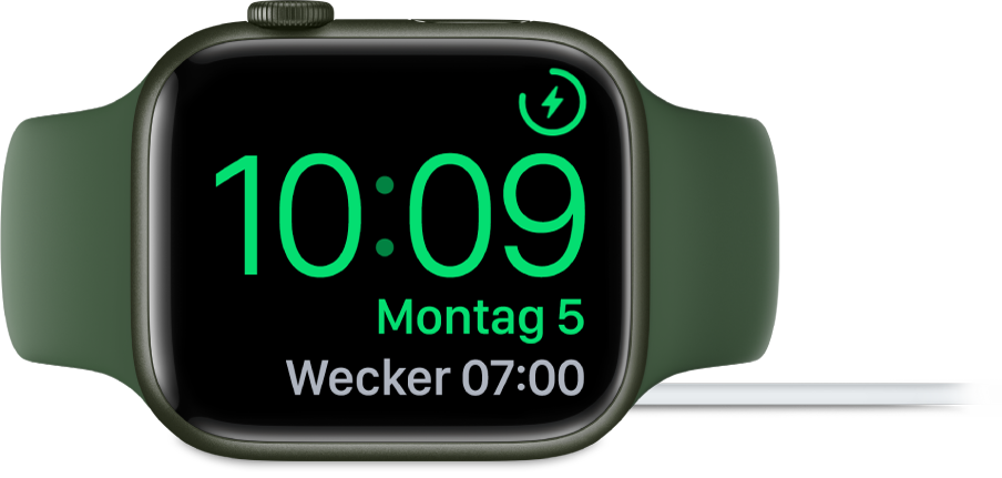 Eine auf die rechte Seite gedrehte Apple Watch, an die das Ladegerät angeschlossen ist und auf deren Display oben rechts das Ladesymbol, darunter die aktuelle Uhrzeit und die Uhrzeit für den nächsten Wecker angezeigt werden.