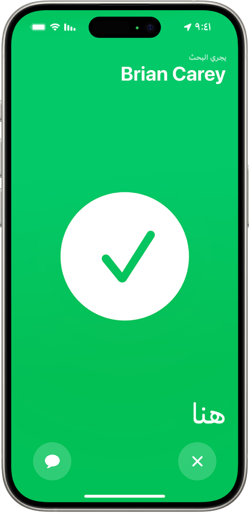 شاشة iPhone خضراء وفي وسطها علامة اختيار كبيرة. اسم الشخص الذي يجري تحديد موقعه يظهر في الزاوية العلوية اليمنى، وكلمة "هنا" في الزاوية السفلية اليمنى، مما يشير إلى أن اللقاء كان ناجحًا.