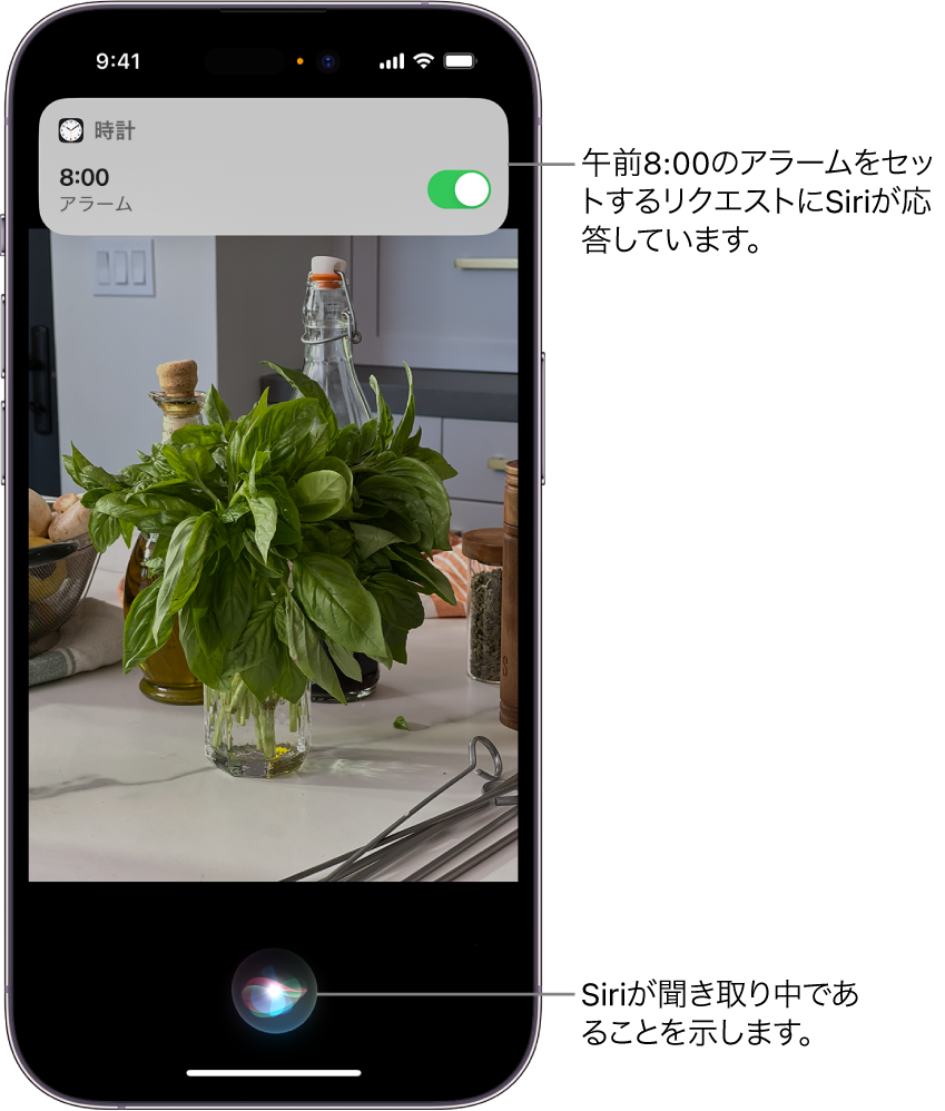 iPhoneの画面。画面上部近くに時計アプリからの通知があり、朝8時にアラームがセットされていることが表示されています。画面下部にあるアイコンは、Siriが聞き取り中であることを示します。