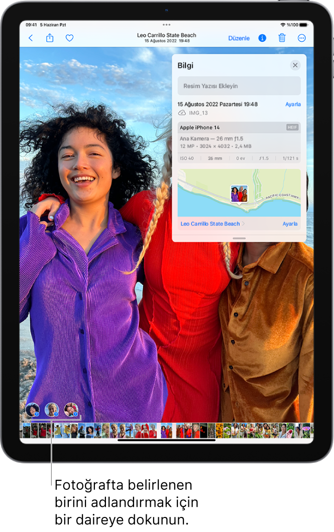 iPad ekranında Fotoğraflar uygulamasında açılmış bir fotoğraf gösteriliyor. Fotoğrafın sol alt köşesinde, fotoğrafta görünen kişilerin yanında soru işareti var.