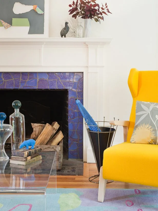 A bold, vivid shade of royal blue surrounds the fireplace in this striking living room. The blue surround provides a lovely contrast — in both color and style — to the traditional white mantel.