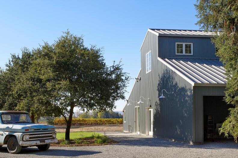 A view of the metal barn, vintage truck and vineyards in the rear. 