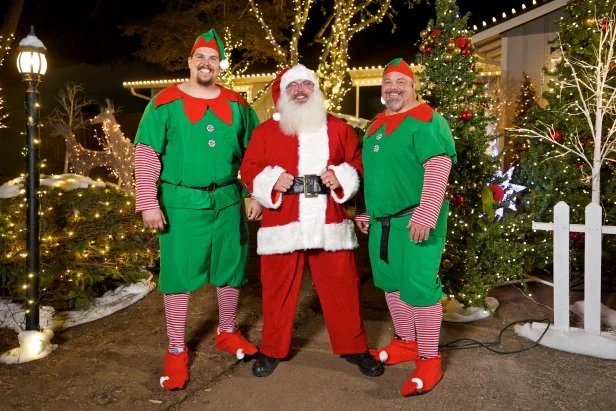 Host Albie Mushaney and his strongman elves pose outside of Sara's new home, as seen on You'll Be Home for Christmas.