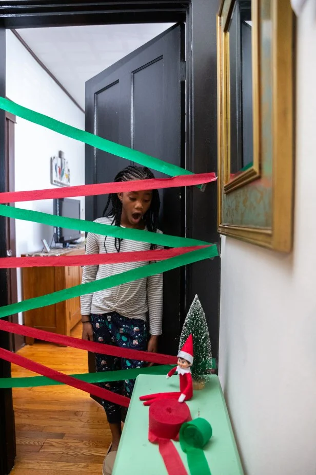 A child stands in a doorway with red and green streamers across it.