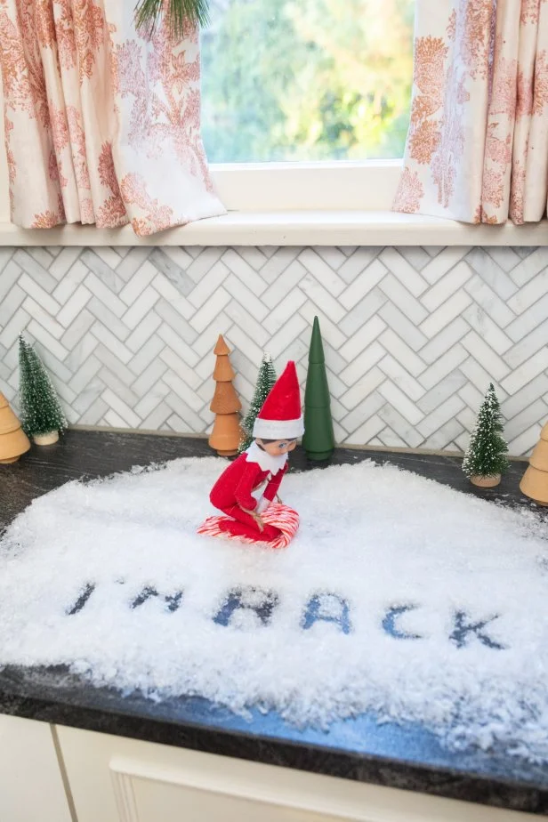 An elf on a candy cane sled rides through fake snow.