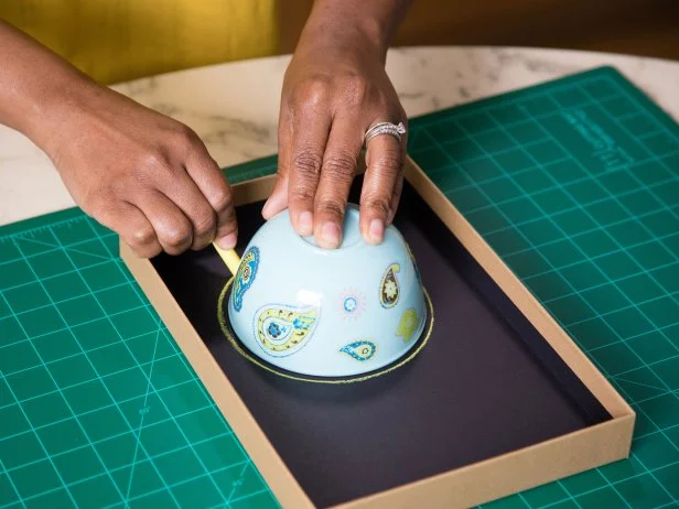 A bowl is used to trace a perfect circle in a shoebox lid.