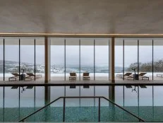 Windows over an indoor swimming pool reveal snowcapped hills