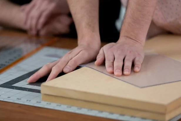 Once the acrylic has been scored, place the sheet onto a piece of scrap wood to evenly break off the corners. Tip: Line up the scored corner along the edge of the wood and press down until it snaps off.