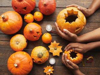 From above view shot of hands holding pumpkin for Hallowing party on dark brown wooden table