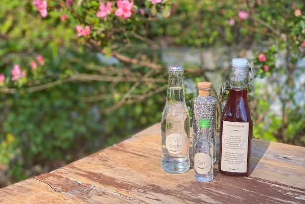 Bottle of Lavender Simple Syrup, Gin, Club Soda, Dried Herbs on Table