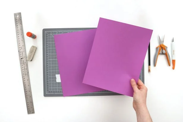 Cut two pieces of colored paper into 7” squares. Your paper should be the weight of printer paper, rather than card stock. Fold them in half diagonally, horizontally, and vertically.