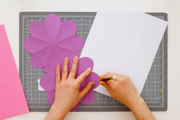 Trace one heart onto scrap paper and cut it out. Cut off about ⅛” all the way around to make a slightly smaller heart pattern. Trace this onto a second color of paper and cut out 8 hearts. You can also cut out a square that fits in the center of the card.