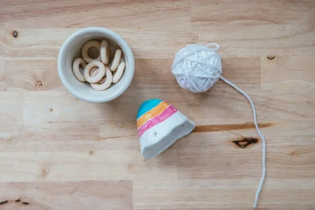 Use cotton twine and small wooden rings to hang the pot (Image 1). Thread twine through the first hole and then through the wooden ring (Image 2). Then, thread through the second hole and back through the wooden ring (Image 3). Repeat again with the third hole and tie off to the beginning of the twine (Image 4).