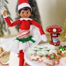 A toy elf holds a tiny gingerbread cookie. 