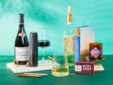 Styled photo of gift ideas for wine lovers including a wine-themed candle, book about wineries and an electric corkscrew.