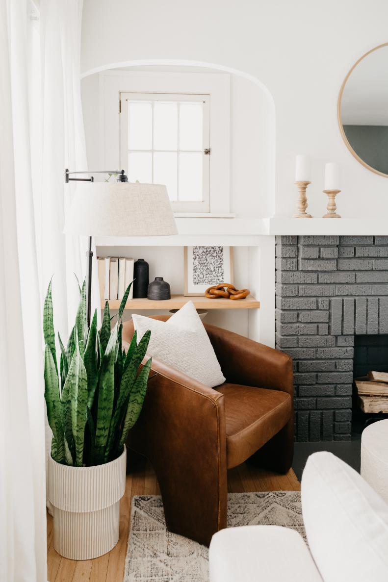 A close-up photo of the corner of a contemporary living room featuring a brown leather armchair and a houseplant.