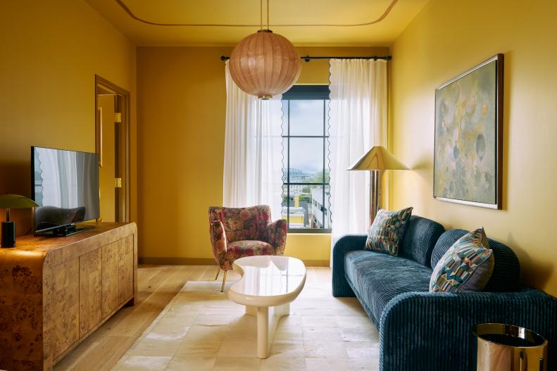 The living room in Hotel Genevieve's Genevieve Suite is washed in floor-to-ceiling color and features a stunning burl wood console and blue velvet sofa.