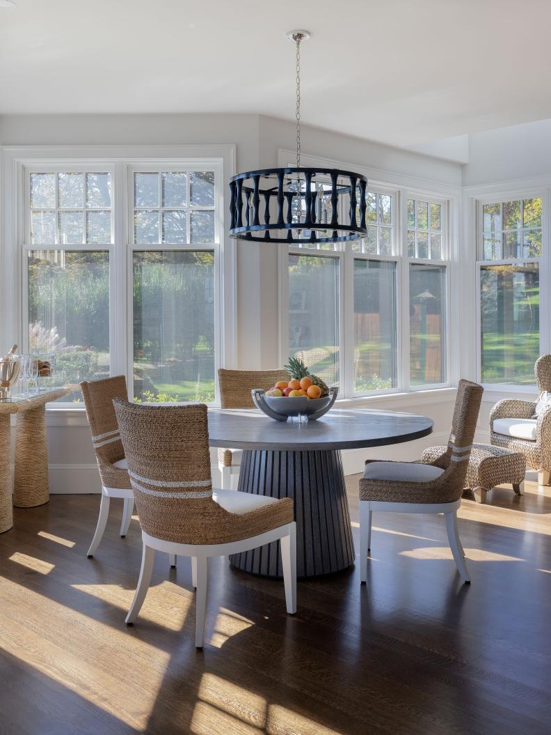 Round breakfast table surrounded by white and brown wicker chairs. 