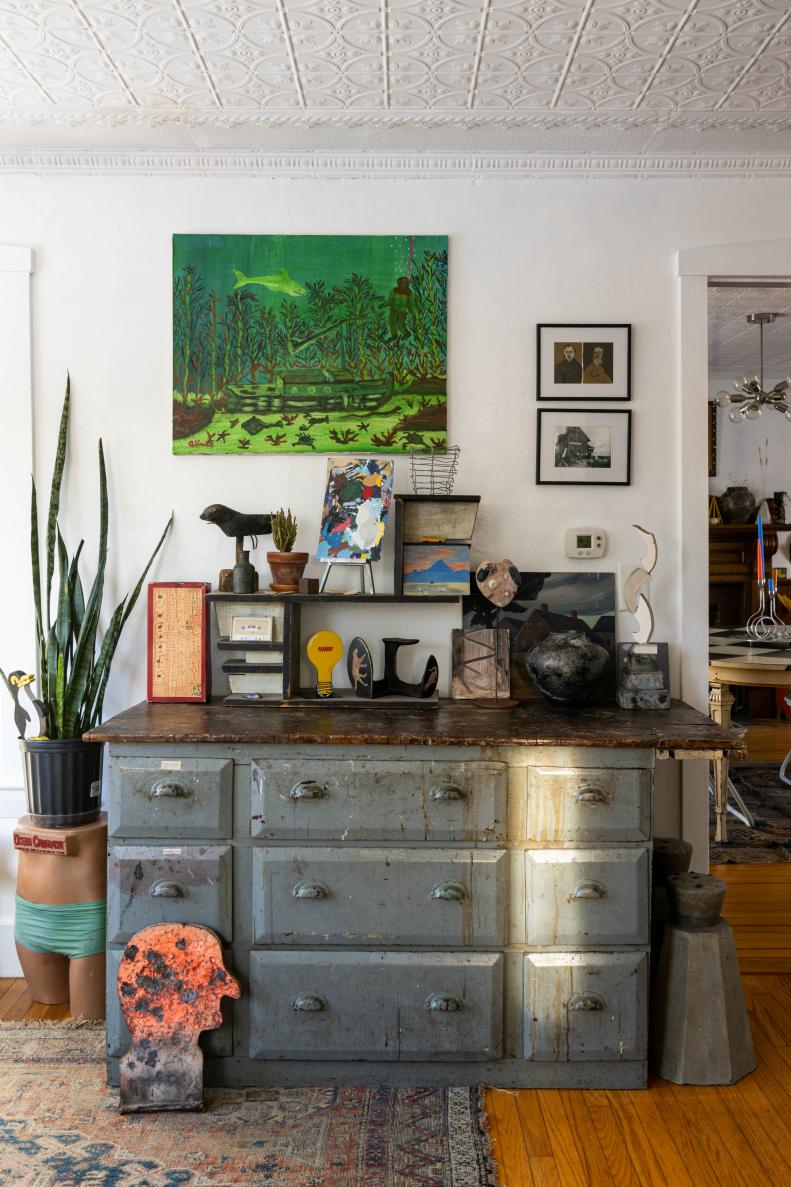 Vintage dresser with paintings, sculptures and old signs displayed