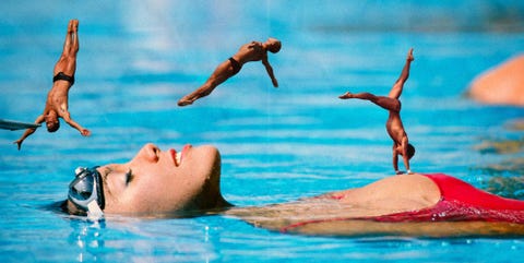 a group of people jumping into a pool