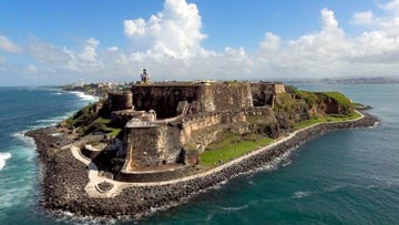 a stone castle on a hill by the ocean