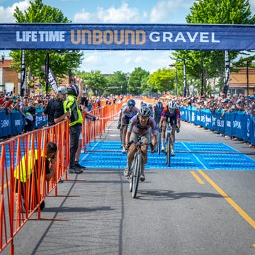 a group of people riding bicycles on a road with a crowd watching