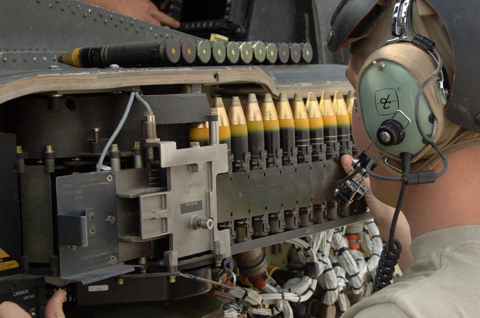 technician loads 30x113mm shells into m230 chain gun cannon of ah 64d attack helicopter