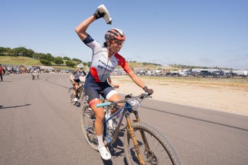 a woman on a mountain bike pours water on her head