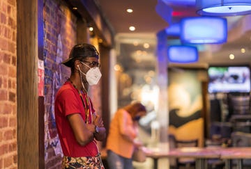 african american gentleman with a hat and glasses waits for his takeout food order during the covid 19 pandemic