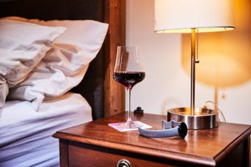 a glass of wine on a bedside table with a fitness watch next to it