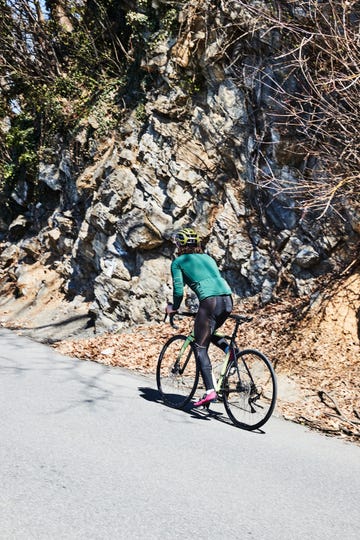 a person riding a bike on a road near a rocky cliff