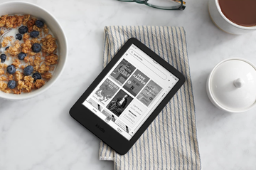 a black electronic device with book covers on the screen sitting on a table