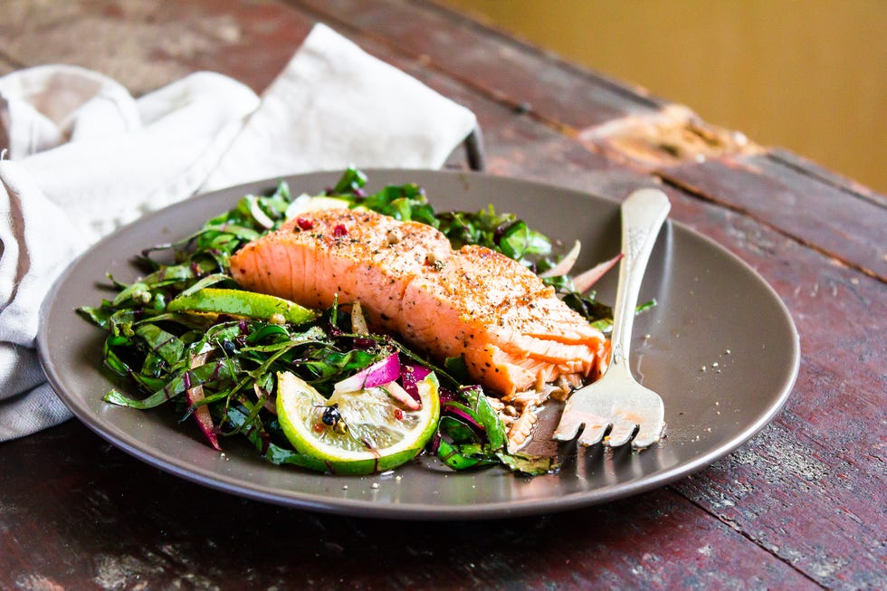 plate of salmon fillet steak roasted with spices served with fresh salad with lime fruit and peppercorns on a wooden table, selective focus picnic fool healthy and organic food concept easter food