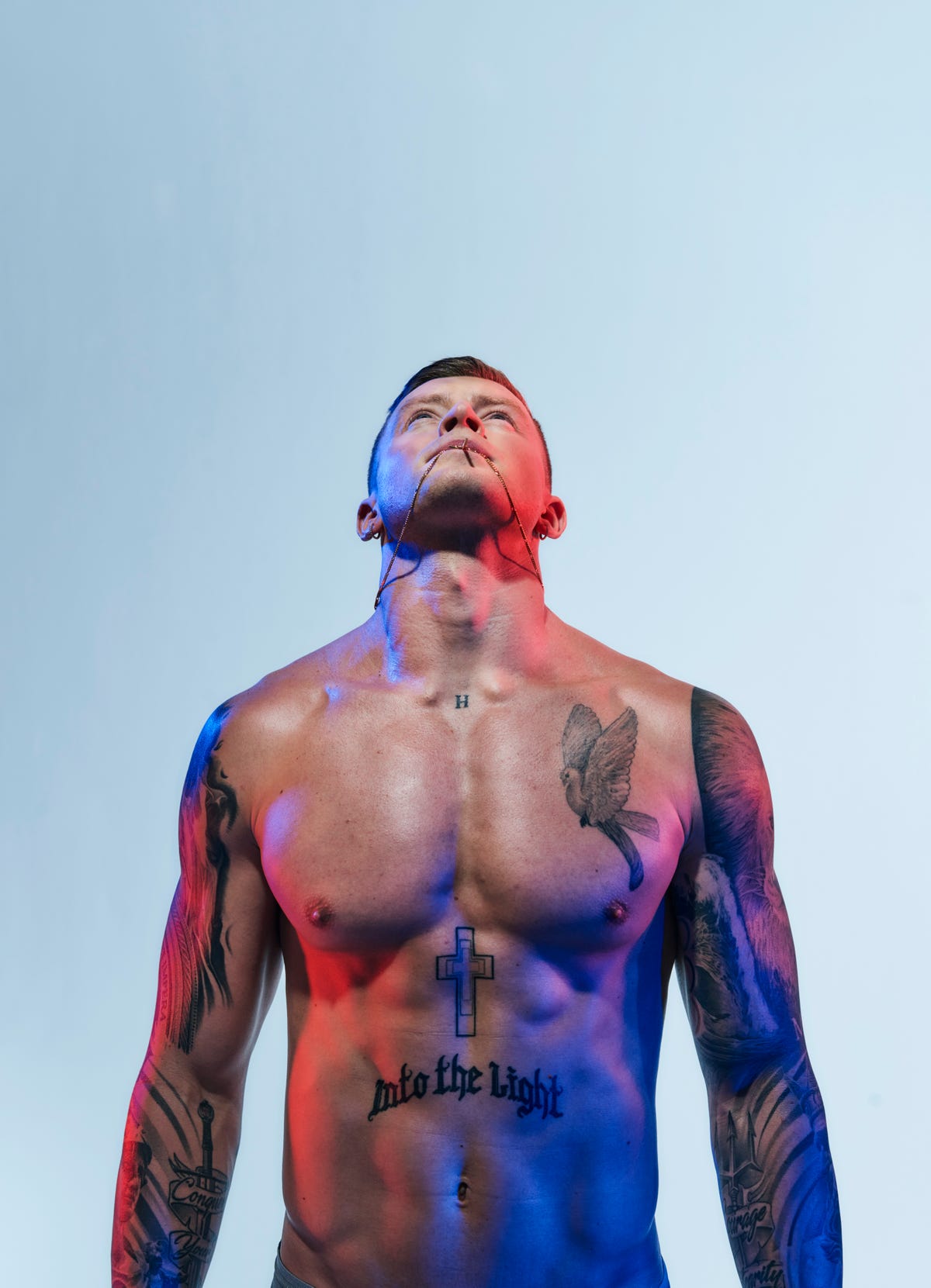 adam peaty looking upwards with a chain in his mouth