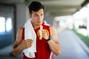 athletic man eating banana after workout outdoors