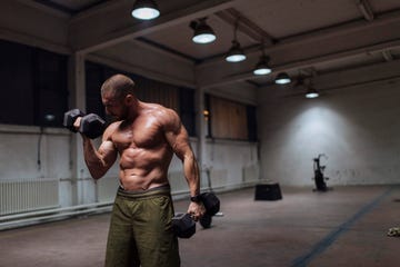 fit young man doing arm exercises with dumbbells