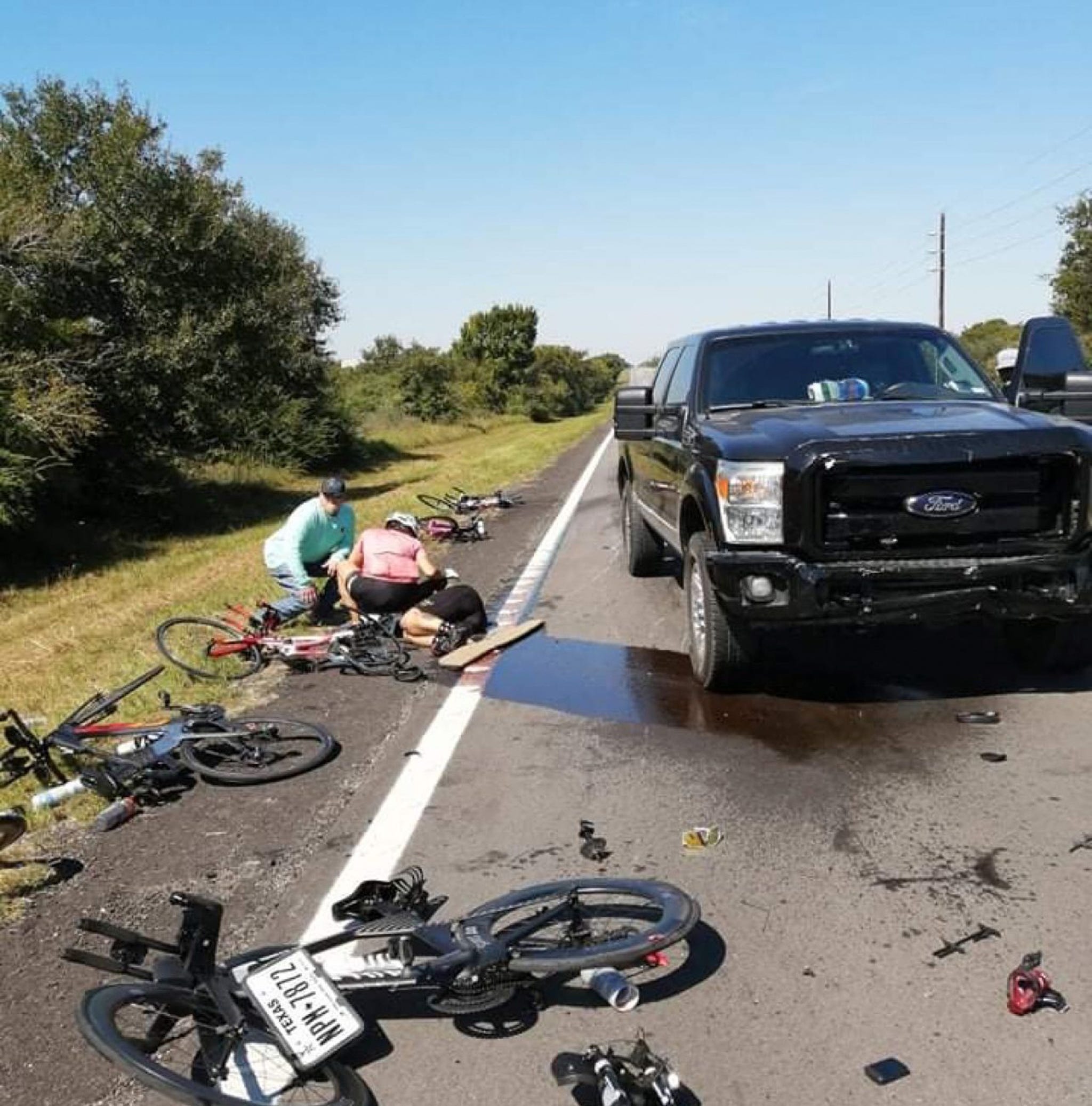 several bikes lay broken on the ground in front of a large pickup truck