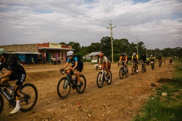 a group of cyclists riding on a dirt road