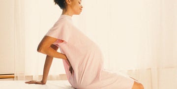 a pregnant black women sitting on a hospital bed