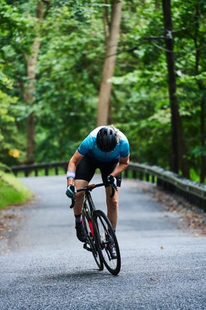 a person riding a bicycle on a road surrounded by trees