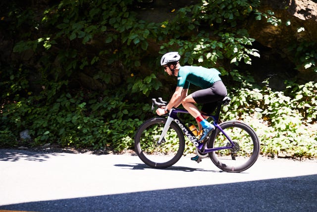 a person riding a road bike on a sunny patch of road