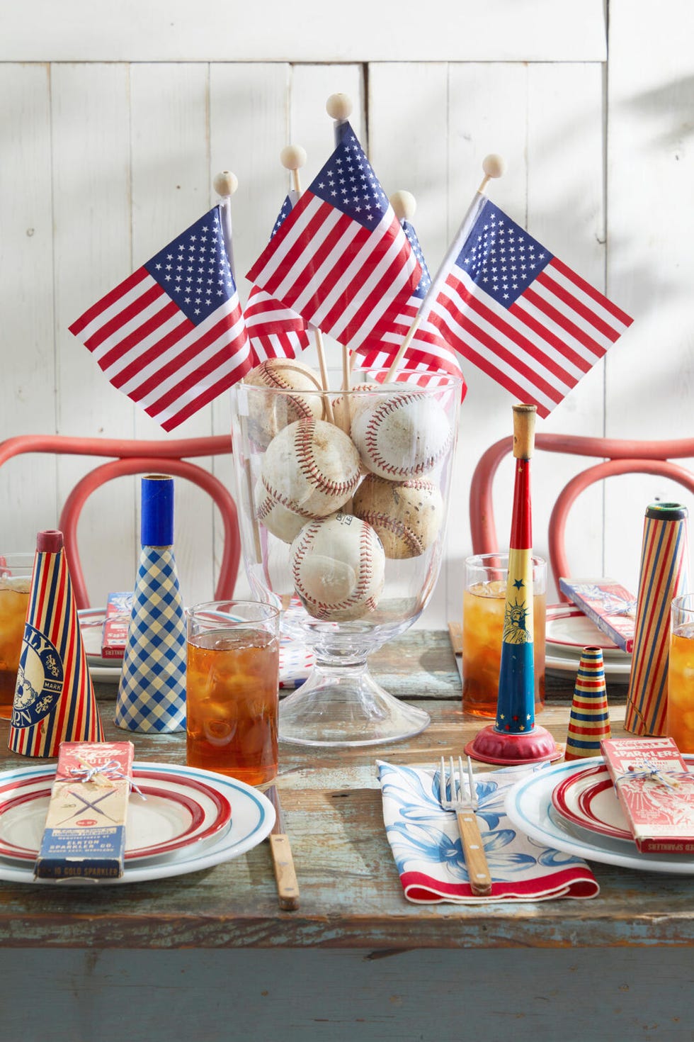 a table with a variety of flags in a baseball filled glass container